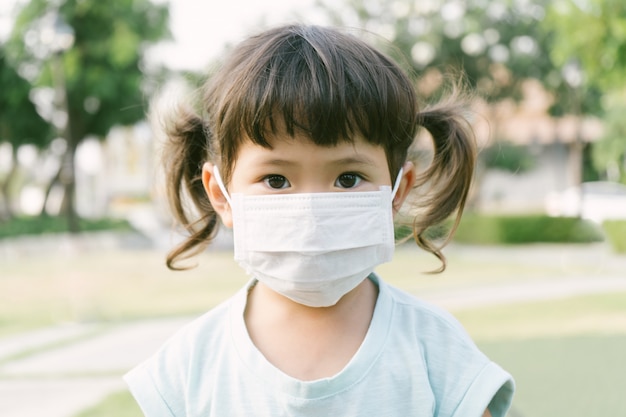 Maschera da portare della piccola ragazza asiatica per proteggere pm2.5 e concetto di Coronavirus