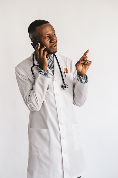 Maschera del primo piano del giovane medico afroamericano che si leva in piedi in uniforme bianca contro il bianco