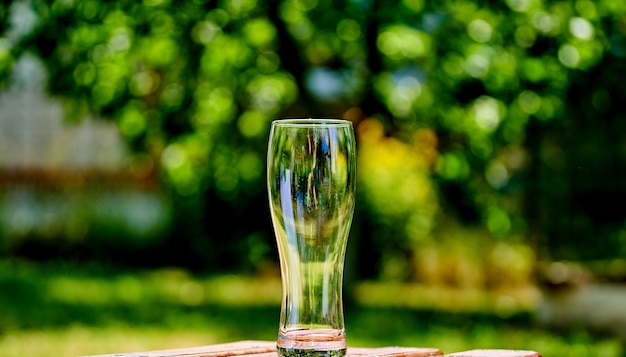 Maschera del primo piano di un bicchiere di birra ampty su una tavola di legno marrone.