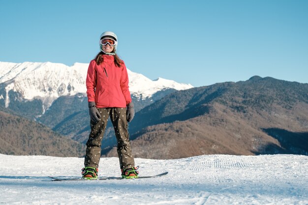 Maschera dello snowboarder felice della giovane signora sui pendii