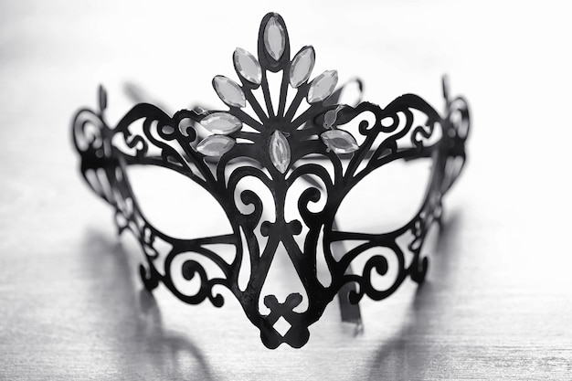 Maschera di carnevale sul tavolo. Il tema del camuffamento in data durante un carnevale. Maschera veneziana su un tavolo di legno in bianco e nero.