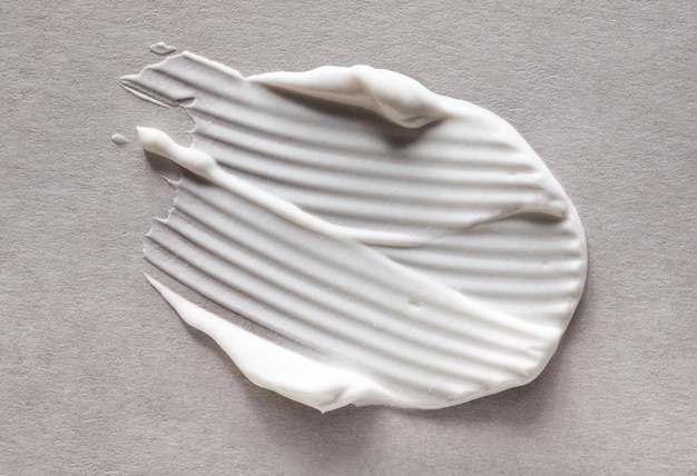 Maschera di crema bianca cosmetica macchia di consistenza isolata su sfondo di consistenza di carta artigianale beige