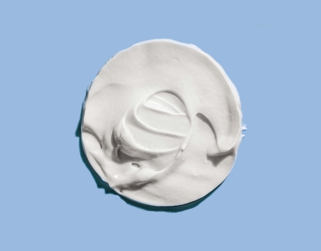 Maschera di crema cosmetica bianca macchia di consistenza isolata su sfondo blu