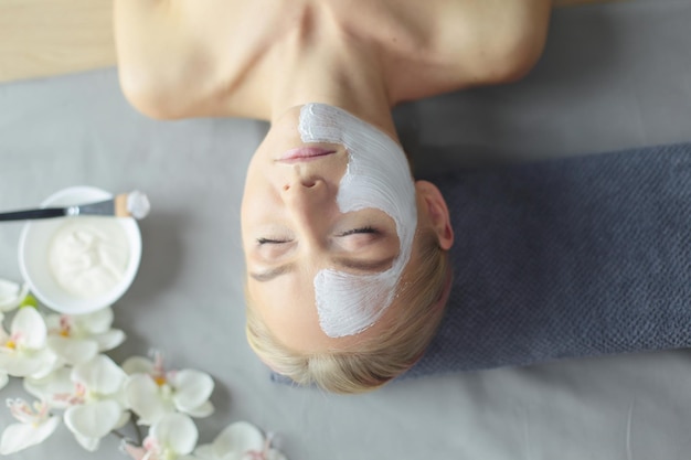 Maschera faccialebella ragazza alla spa estetista donna che applica maschera facciale