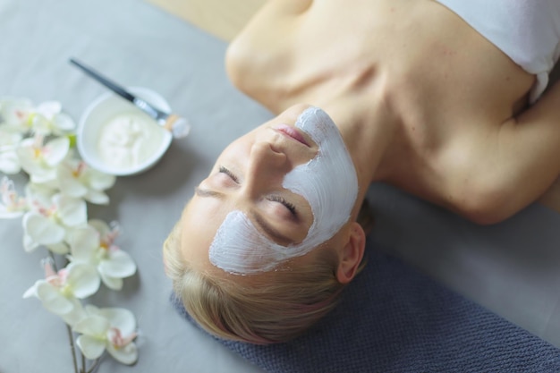 Maschera faccialebella ragazza alla spa estetista donna che applica maschera facciale