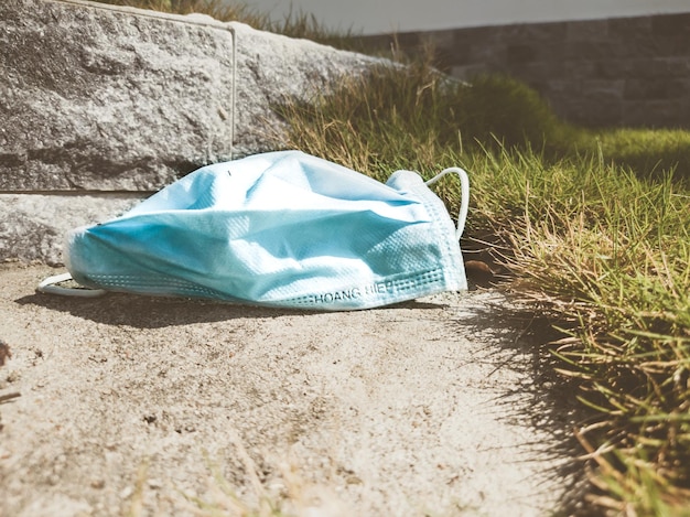 Maschera medica blu usata su terreno e erba primo piano Quarantena Protezione dai virus Situazione ecologica