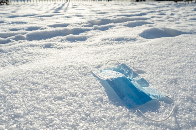 Maschera medica che giace nella neve. Agente protettivo usato contro il virus lanciato in un cumulo di neve