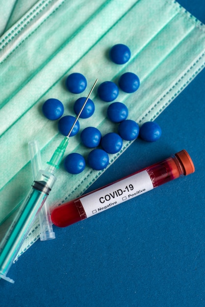 Maschera medica, compresse di compresse con siringa o iniezione e provetta contenente un campione di sangue per testare la presenza di coronavirus / COVID-19.