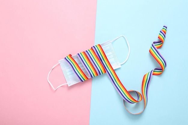 Maschera medica con nastro a nastro arcobaleno LGBT su sfondo rosa blu