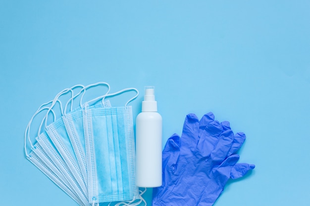 Maschera medica, guanti e disinfettante per le mani per la protezione dalle infezioni su sfondo blu. Vista dall'alto. Disteso.