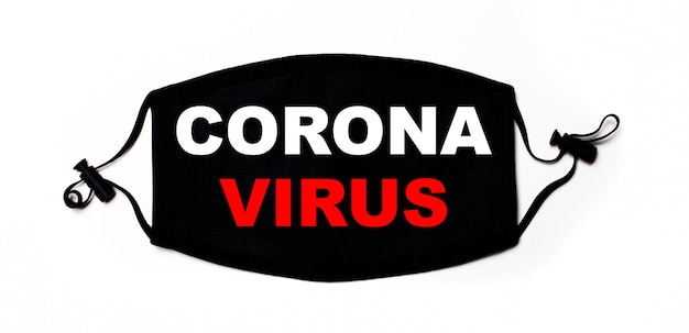 Maschera medica nera su una superficie chiara con la scritta CORONA VIRUS. Prevenzione delle malattie. Concetto medico