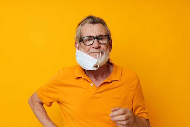 Maschera medica per uomo anziano ritratto sullo sfondo giallo del primo piano della protezione del viso