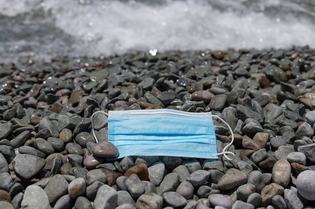 Maschera medica protettiva su una spiaggia di ciottoli