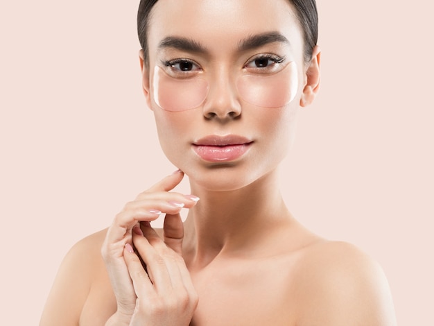 Maschera per gli occhi cosmetico viso donna asiatica. Colore di sfondo. Rosa