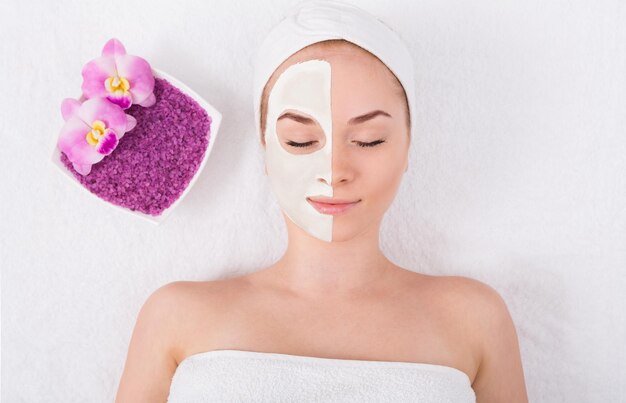 Maschera per il viso al salone spa, trattamento di bellezza. Donna che applica maschera facciale all'argilla, relax, cura della pelle, vista dall'alto, dall'alto