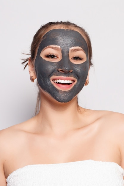 Maschera per il viso della donna. Ritratto di bella ragazza che rimuove la maschera peeling nera cosmetica dalla pelle del viso. Primo piano di giovane donna attraente con trucco naturale e maschera di buccia cosmetica sul viso. Alta risoluzione