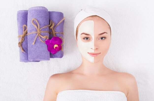 Maschera per il viso, trattamento di bellezza termale. Donna che applica maschera di argilla facciale al salone spa, cura della pelle, vista dall'alto, overhead