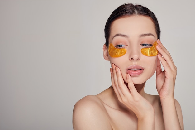 Maschera per la rimozione di rughe, occhiaie. Una donna si prende cura della pelle delicata intorno agli occhi. Procedure cosmetiche.