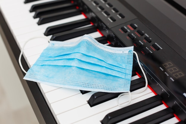 Maschera protettiva per l'influenza medica sul primo piano della tastiera del pianoforte