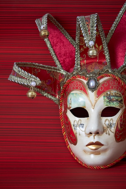 Maschera veneziana tradizionale di carnevale con la decorazione ricca su un fondo rosso, fuoco selettivo