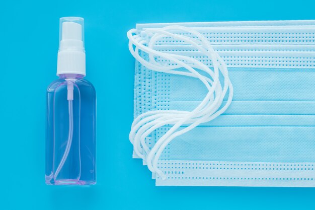 Maschere chirurgiche e disinfettante per le mani. Sfondo blu. Prevenzione del coronavirus.