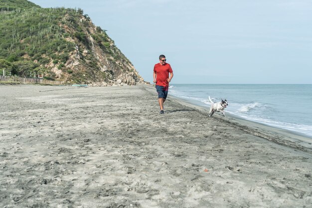 Maschio adulto in abiti casual con un cane in spiaggia