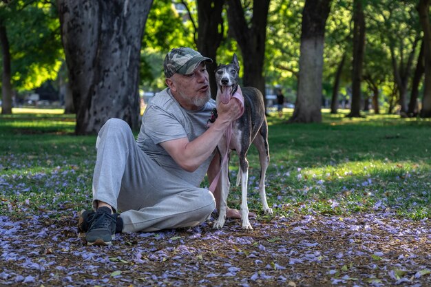 Maschio adulto maturo con cane levriero all'aperto