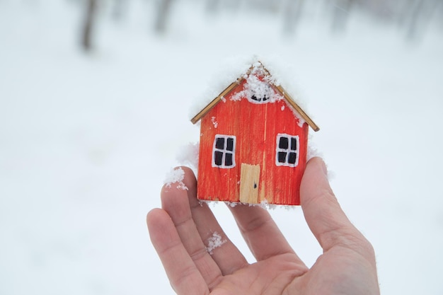 Maschio che mostra la mano al modello di casa in inverno