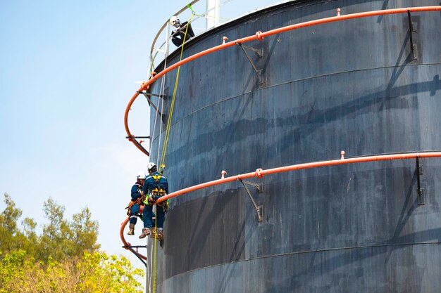 Maschio due lavoratori corda verso il basso accesso ispezione di sicurezza del serbatoio di stoccaggio di riparazione dell'acqua antincendio del tubo