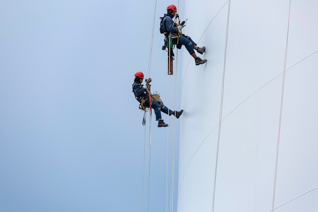 Maschio due lavoratori giù altezza serbatoio fune accesso ispezione di spessore shell piastra serbatoio di stoccaggio gas propano sicurezza lavoro in quota.