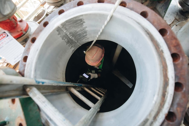 Maschio nella sostanza chimica del processo di ispezione del lavoro nel serbatoio inossidabile chimico