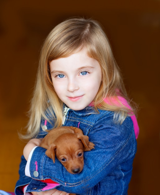 mascotte del cucciolo del mini pinnscher con la ragazza bionda del bambino