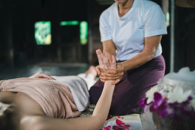 Massaggi e spa trattamento rilassante della sindrome dell'ufficio con pietre calde tradizionali massaggio tailandese stile Asain massaggiatrice femminile che fa massaggio alle mani trattare lo stress per la donna