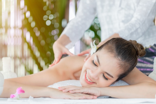 Massaggiatore che fa massaggio sul corpo della donna nel salone spa Donna asiatica sul lettino da massaggio relax e stile di vita massaggio mani trattamento Concetto di trattamento di bellezza