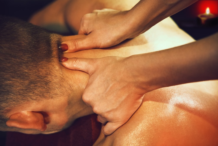 Foto massaggiatore che massaggia il collo di un uomo nel salone della spa.