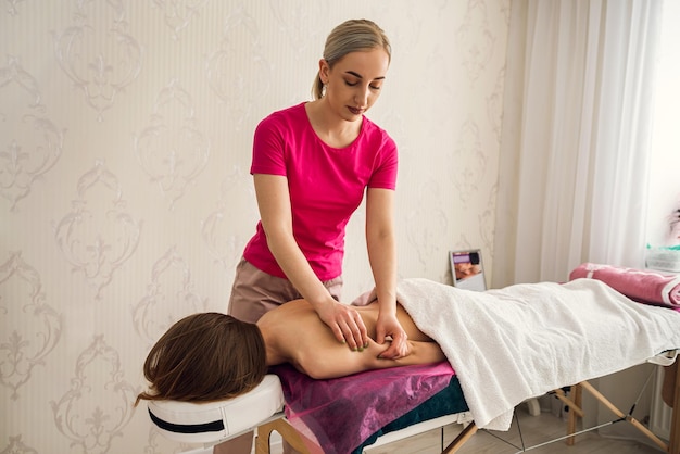 Massaggiatore femminile che fa massaggio anticellulite per perdere peso sulla schiena al cliente donna