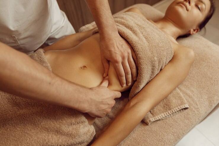Foto massaggiatore maschio coccole costole a giovane donna sottile in asciugamano, massaggio professionale. massaggio e relax, cura del corpo e della pelle. signora attraente nel salone della stazione termale