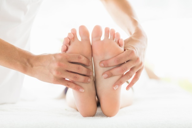 Massaggiatore ritagliato che dà massaggio ai piedi alla donna