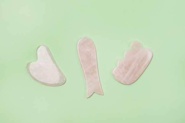 Massaggiatori Gua Sha su sfondo verde Pietra di giada rosa per viso e corpo