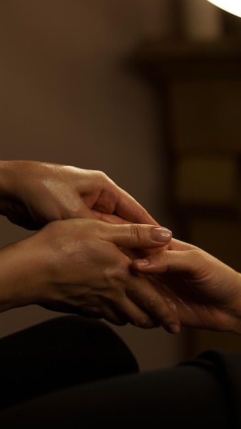 massaggio alle mani con olio per il corpo in un primo piano di una sala massaggi su uno sfondo scuro
