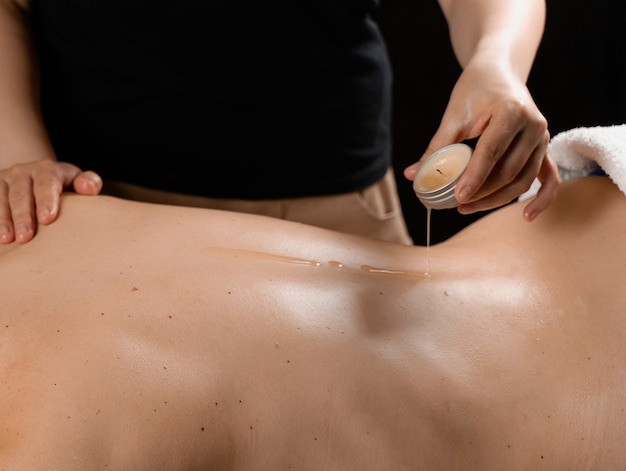 Massaggio corpo ceretta con candela. Procedura di bellezza spa. Massaggio thailandese con cera calda.