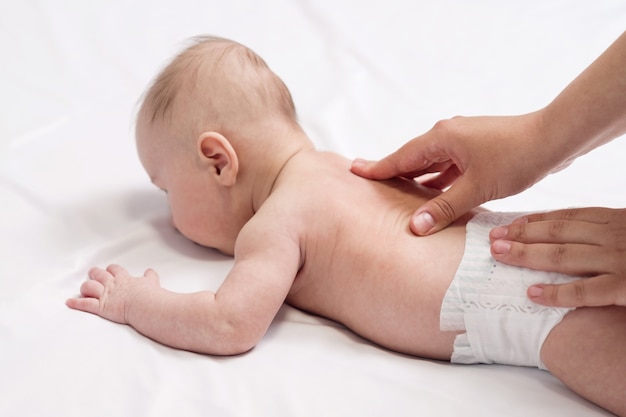 Massaggio del bambino, mani del primo piano sulla schiena del bambino