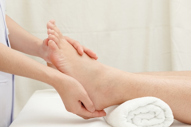Massaggio del piede, mani del terapista che massaggiano il piede femminile