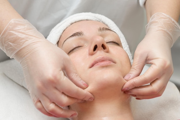 Massaggio facciale Giovane donna che riceve un massaggio termale presso il salone termale di bellezza Cura della pelle della stazione termale Cosmetologia