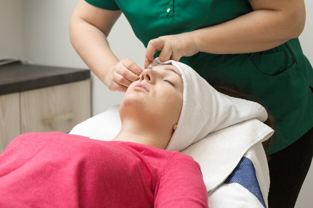 Massaggio viso Giovane donna che riceve un massaggio termale presso il salone di bellezza spa Cura della pelle spa