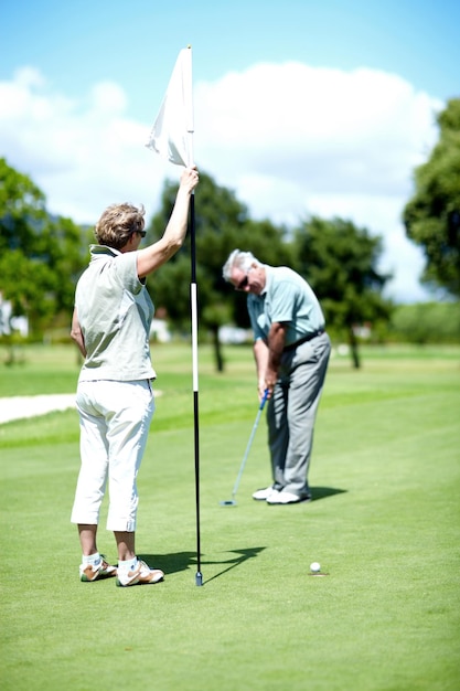 Master of the Holeinone Una donna anziana che tiene una bandiera mentre suo marito mette per birdie