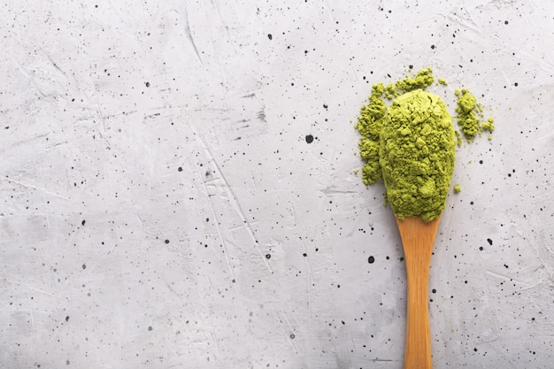 Matcha del tè verde in un cucchiaio su superficie di calcestruzzo. Colpo da vicino