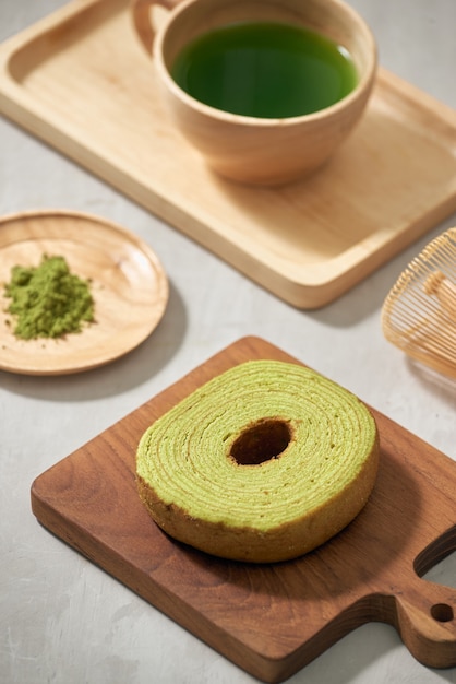 Matcha del tè verde in una tazza di legno con il dolce tedesco sul primo piano marrone della stuoia