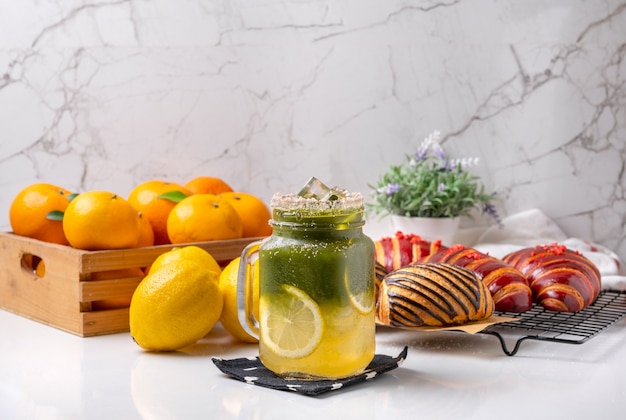 Matcha freddo al miele di limone decorato con limone su un tavolo bianco