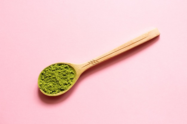 Matcha. Tè verde in polvere giapponese in un cucchiaio su uno sfondo rosa.